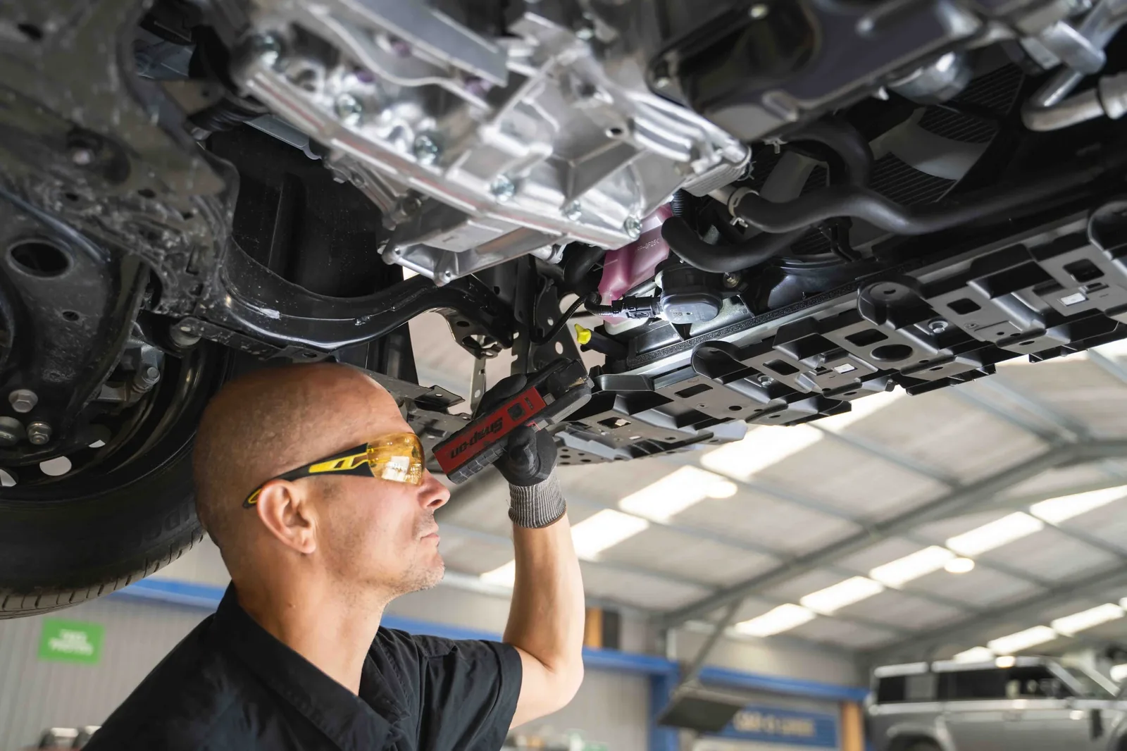 Mechanic inspecting the underside of a vehicle for a water leak