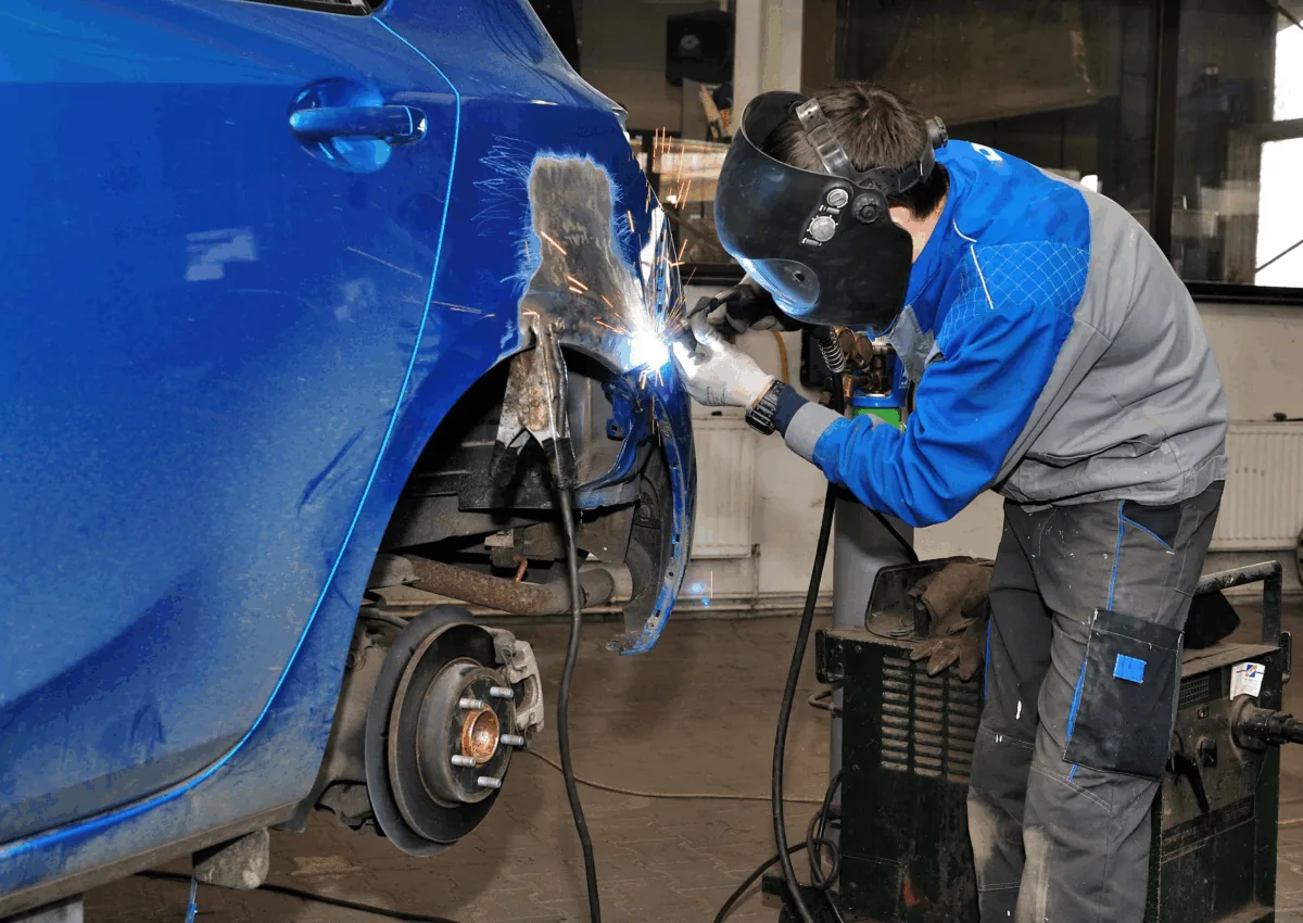 Panel beater welding a quarter panel during a structural crash repair